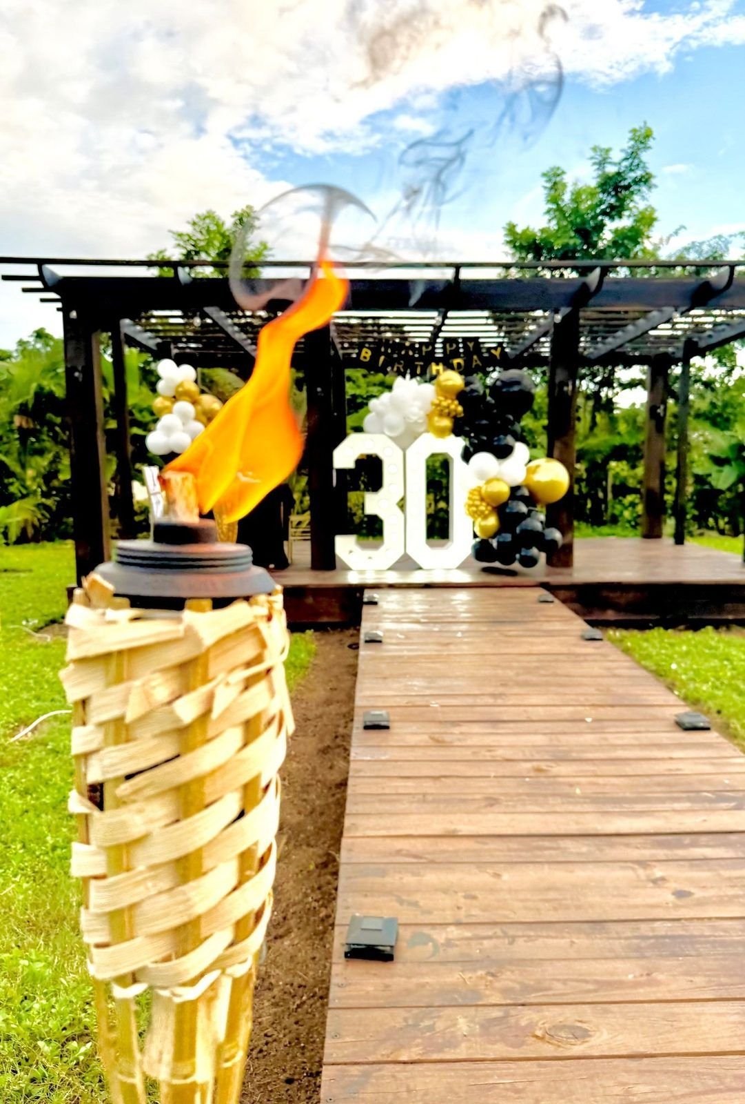 Tiki torch lighting the walkway to a birthday setup