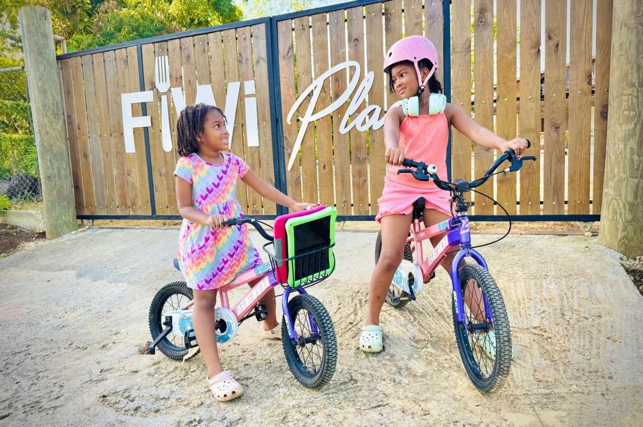 Two girls on bikes at the FiWi Place gate