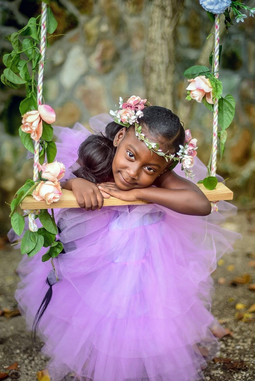 Little girl in a lilac tutu on a flower swing