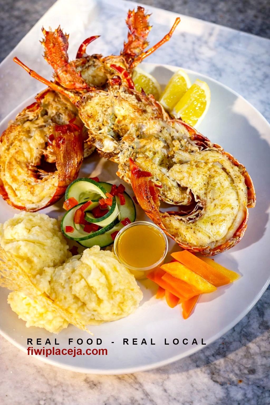 Grilled lobster dinner with mashed potatoes, vegetables and lemon